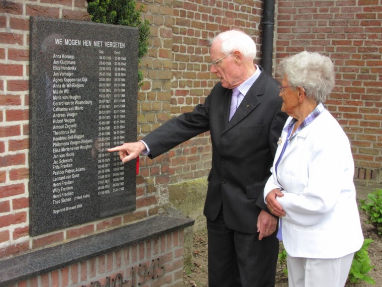 Pater Harrie Verhoeven wijst Lies van Houts de naam van haar broer Jan aan op het Ospelse oorlogsmonument. (foto – Sjef Geuns).