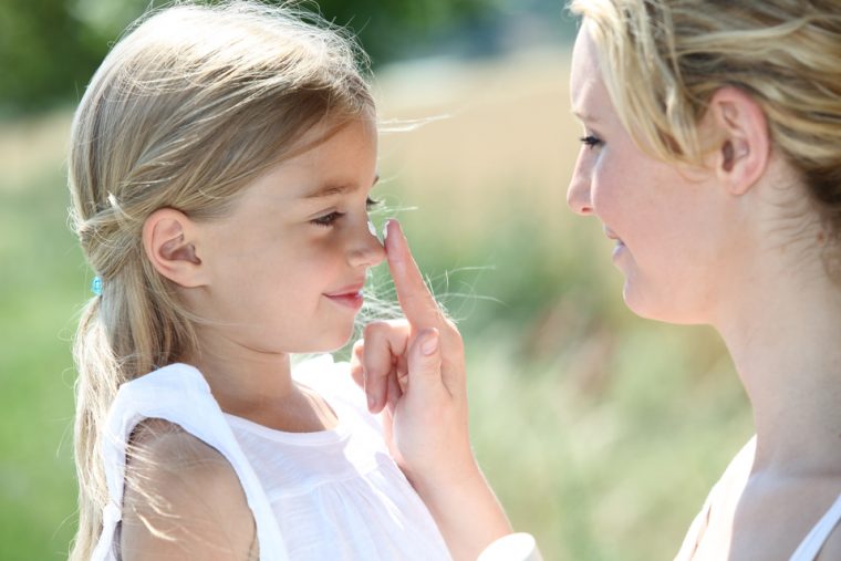 Mother and daughter putting sun protection on their face