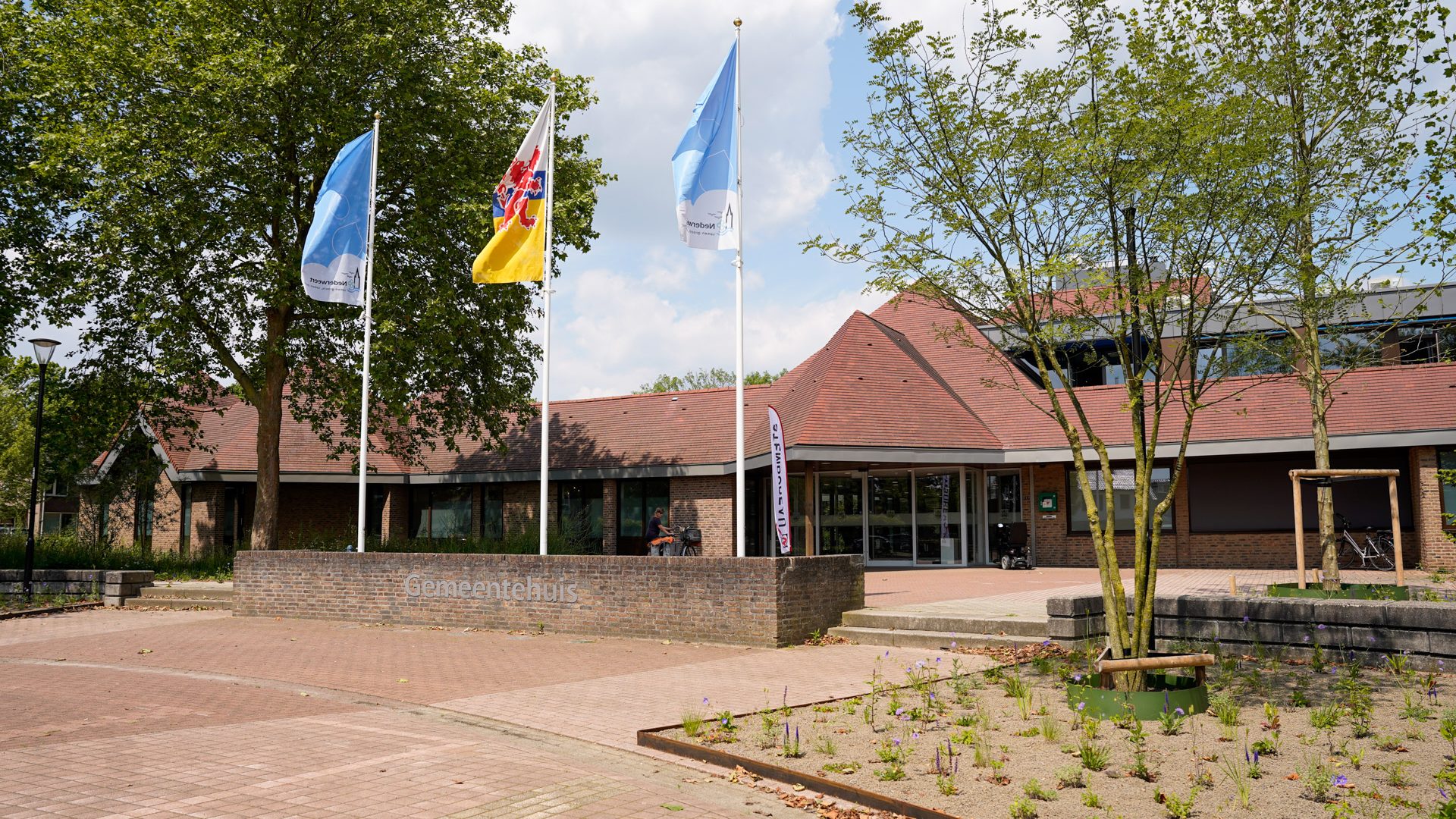 Het gemeentehuis aan het Raadhuisplein met de Nederweerter vlaggen in top.