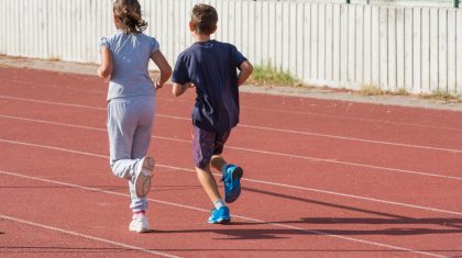 Atletiek-sport-jeugd-rennen girl and boy jogging on tartan track