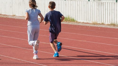 girl and boy jogging on tartan track