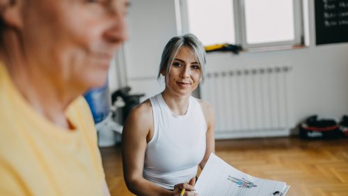 Senior man exercising with the assistance from young woman - personal trainer