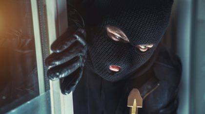 Overval-inbreker Masked burglar with torch and crowbar breaking and entering into a house - shot with dramatic motion