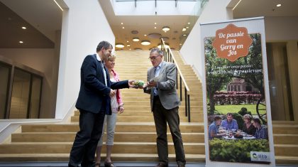 Jos en Gerrie Mans overhandigen wethouder Litjens een doosje eieren.