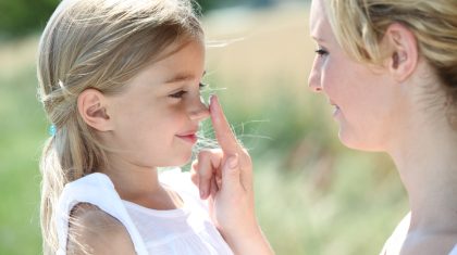 Mother and daughter putting sun protection on their face